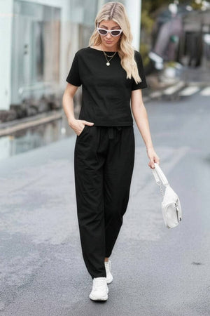 Woman wearing black cotton linen set with short-sleeve top and straight-leg pants walking outdoors
