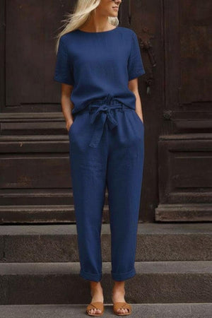 Woman wearing navy blue breathable cotton linen set with relaxed short-sleeve top and straight-leg pants with drawstring waist.