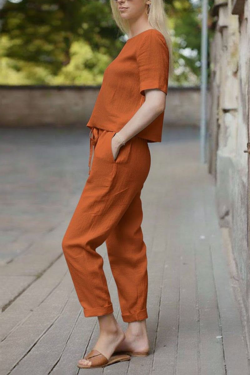 Woman wearing relaxed fit orange cotton linen set with short sleeve top and straight-leg pants outdoors