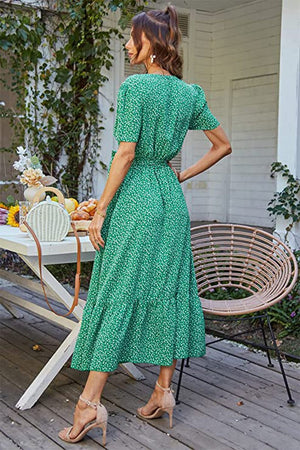 Back view of woman wearing a green charming floral boho maxi dress with short sleeves and ruffle hem standing on wooden patio