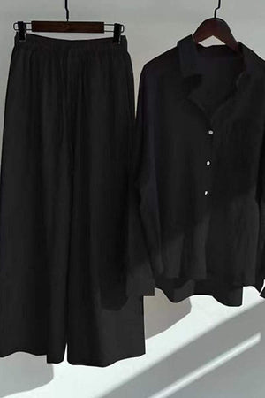 Black oversized shirt and palazzo pants two-piece linen set hanging on wooden hangers