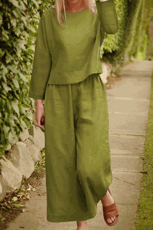Woman wearing loose solid color two-piece set in olive green with long sleeves and wide-leg pants outdoors