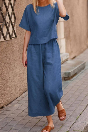 Woman wearing blue loose fit co-ord set with wide-leg pants and short-sleeve top walking on street