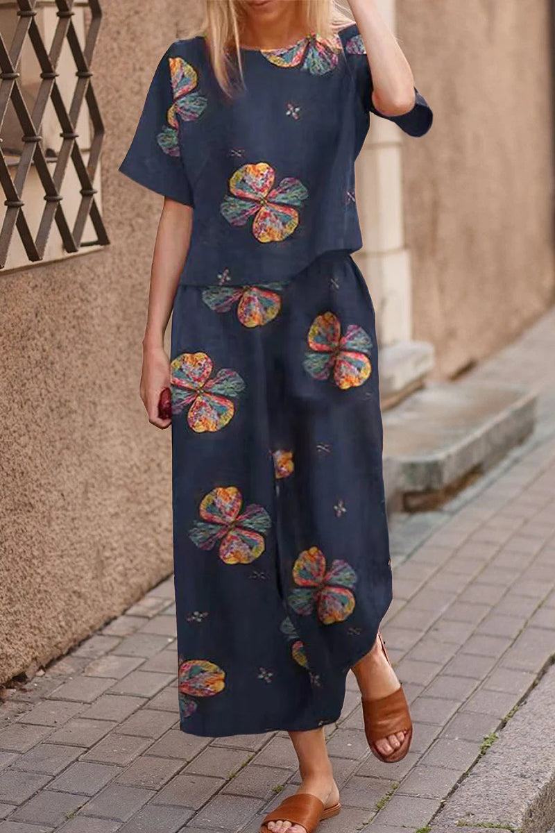 woman wearing navy blue loose fit co-ord set with colorful floral prints and brown sandals walking on sidewalk
