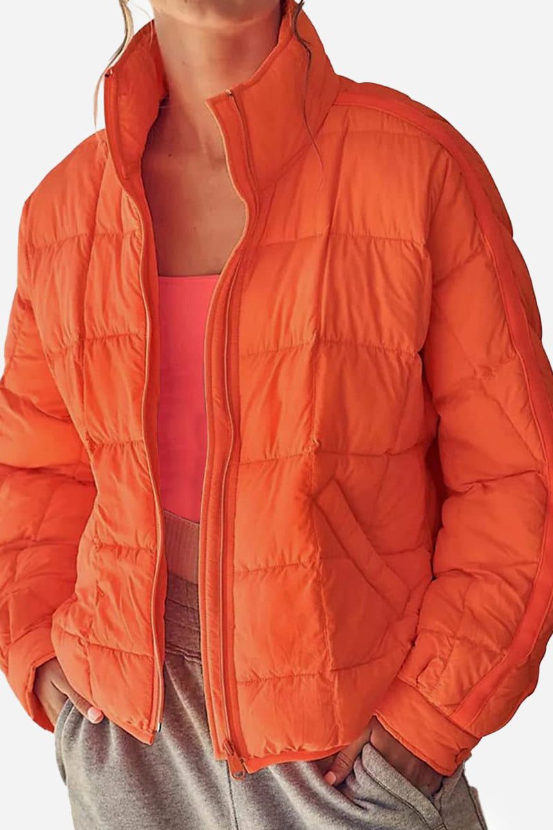 Orange lightweight puffer travel jacket with quilted design and front zipper, styled casually.