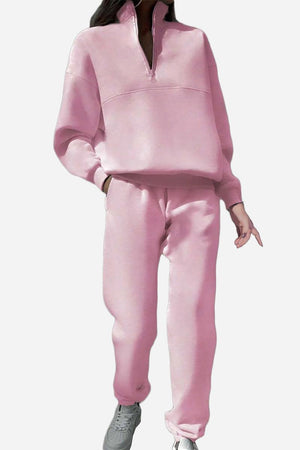 Pink cotton-blended two-piece tracksuit with high collar and zipper, styled with sneakers.