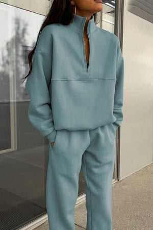 woman wearing light blue cotton-blended two-piece tracksuit with high collar and zipper standing outdoors