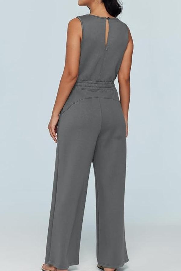 Back view of a woman wearing a gray sleeveless wide leg pants jumpsuit with a drawstring waist and keyhole detail.