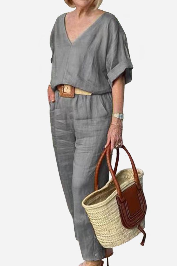 Woman wearing grey V-neck cotton two-piece trouser set holding a woven handbag