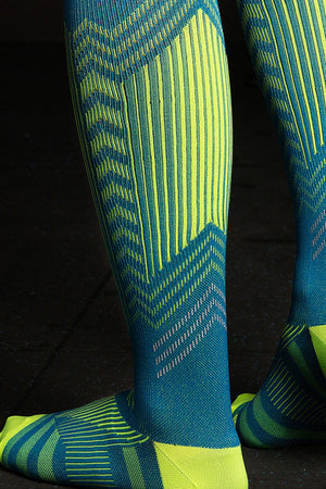 Close-up of legs wearing premium compression socks with blue and yellow geometric patterns for travel and leg fatigue relief
