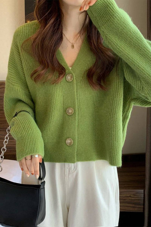 Green casual loose boxy cardigan with buttons worn with white pants and black handbag