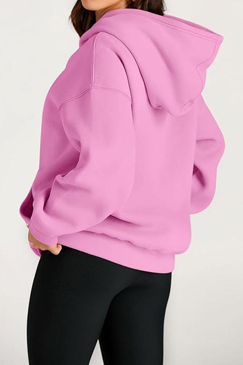 Woman wearing a pink oversized fleece-lined hoodie with black leggings from the back angle
