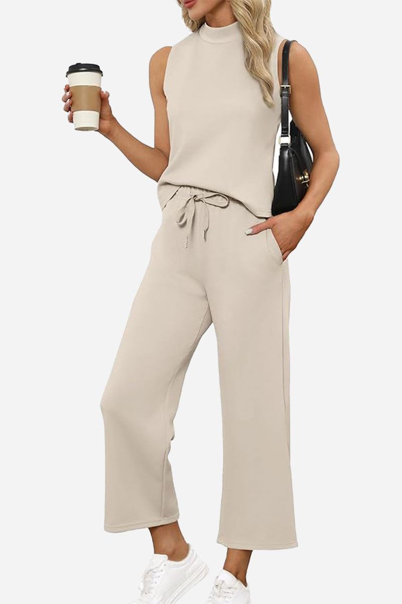 Woman wearing beige Cotton Chic Sleeveless two-piece outfit with sleeveless top and wide-leg pants holding coffee cup and black handbag