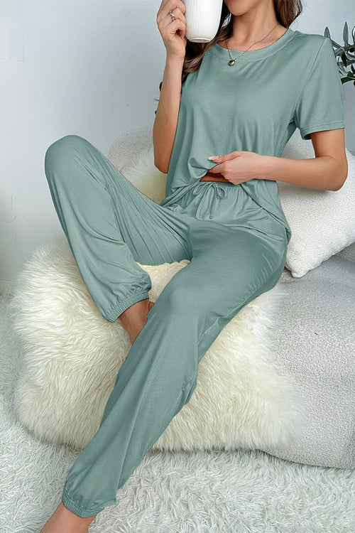 Woman wearing soft green My Go To Loungewear two-piece set relaxing with a cup of coffee.