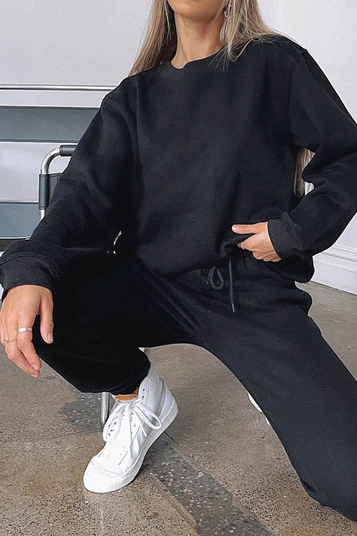 Woman wearing black Classic Comfort Athleisure set with white sneakers sitting on floor