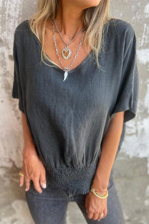 Women wearing a charcoal grey pure linen short-sleeve blouse with V-neck and smocked waist detail.