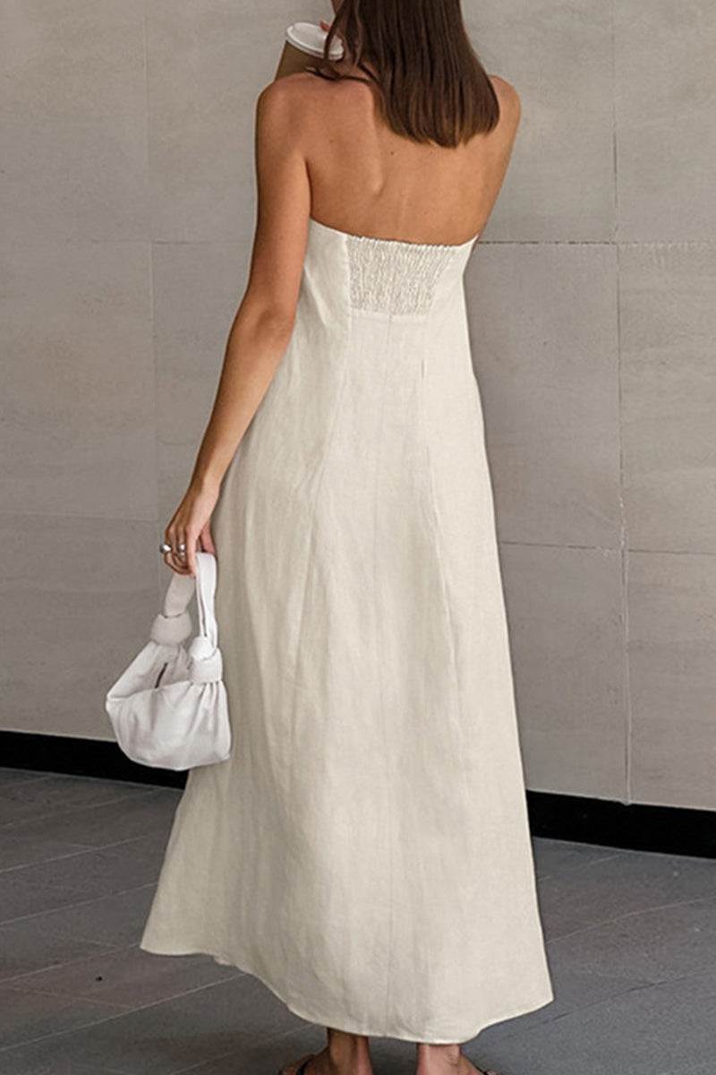 Back view of a woman wearing a strapless beige cotton linen blend maxi dress with an elastic back panel, holding a white handbag.