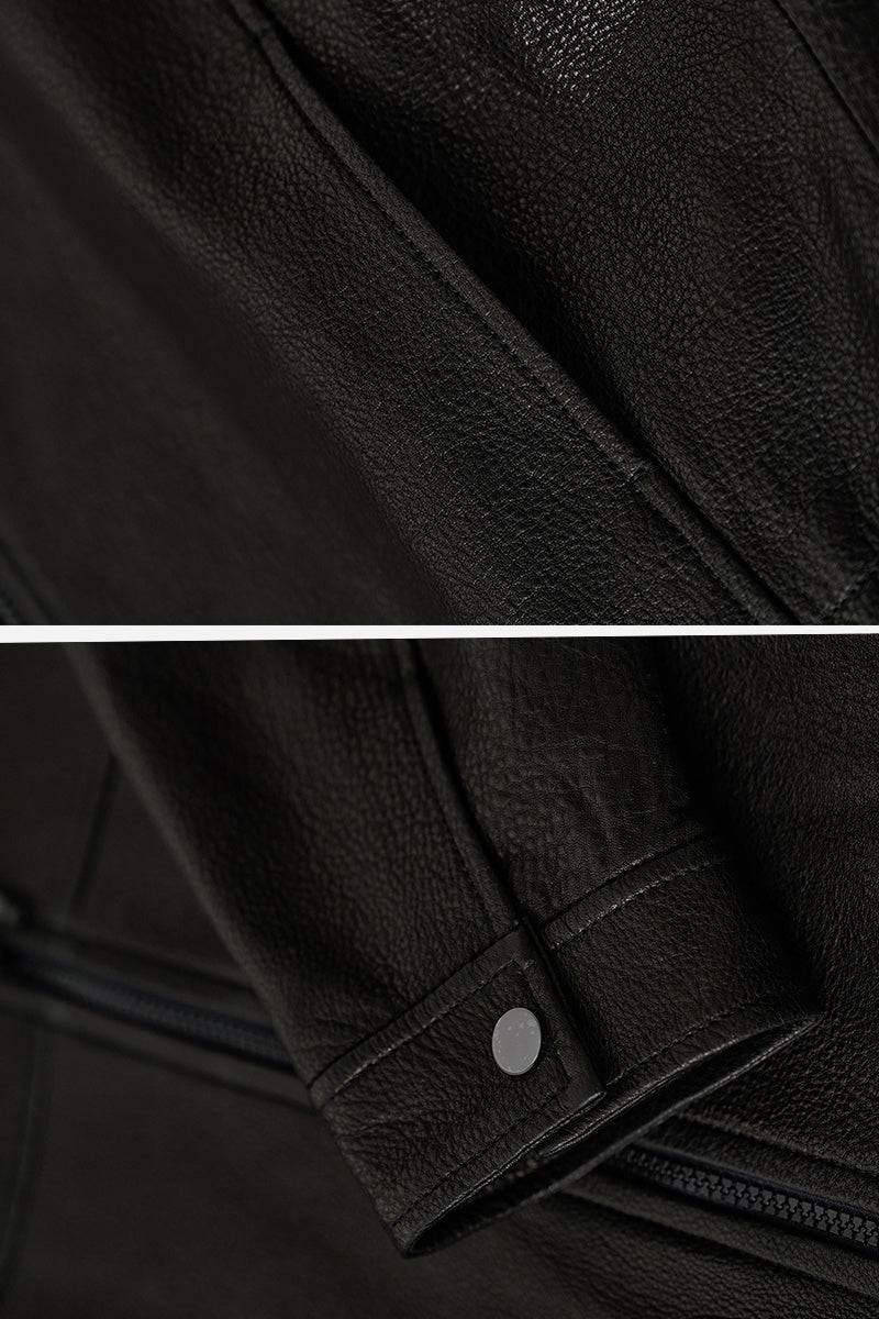 Close-up of black sheepskin leather jacket texture and sleeve detail with snap button, showcasing genuine soft leather material.