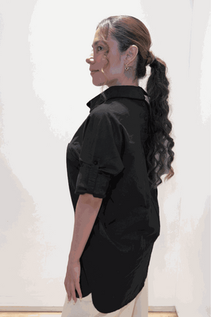 Woman wearing black oversized linen-leaved-in set shirt with rolled sleeves, side view