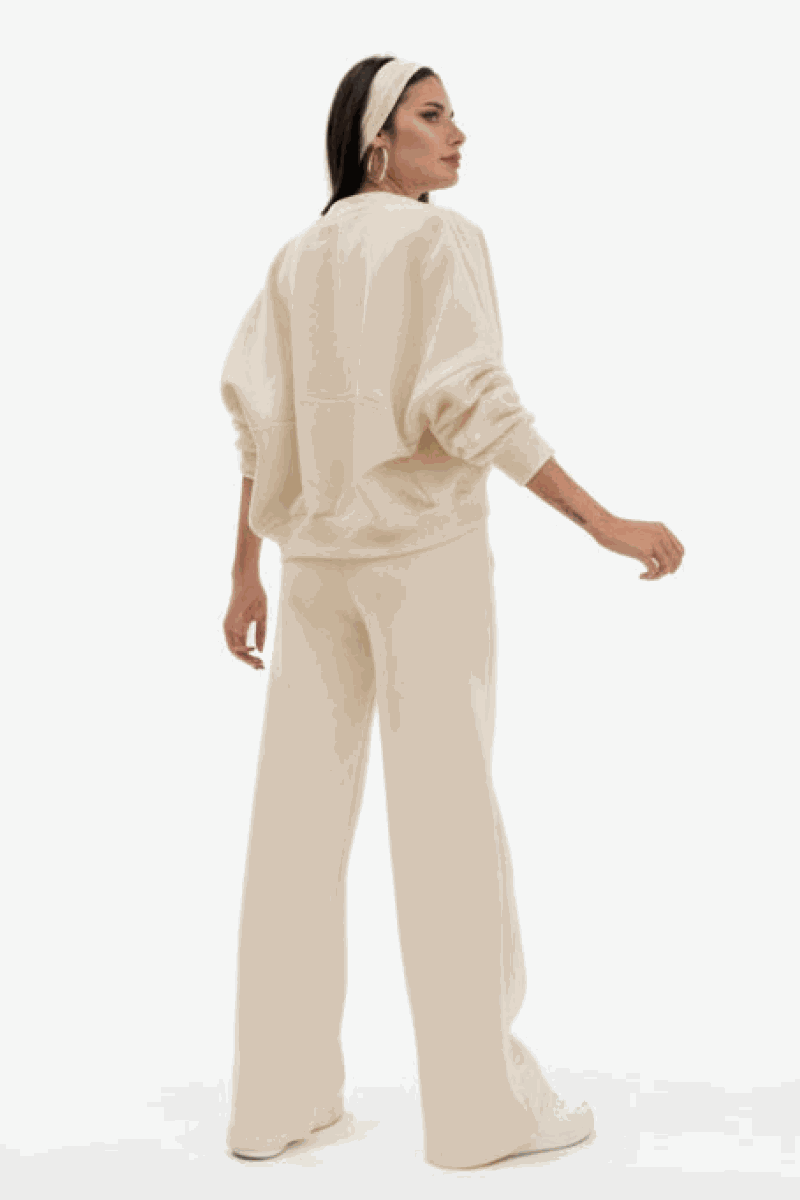 Woman wearing The Voyager Zip Set beige zip-front sweatshirt and wide-leg joggers from back with relaxed fit and pockets