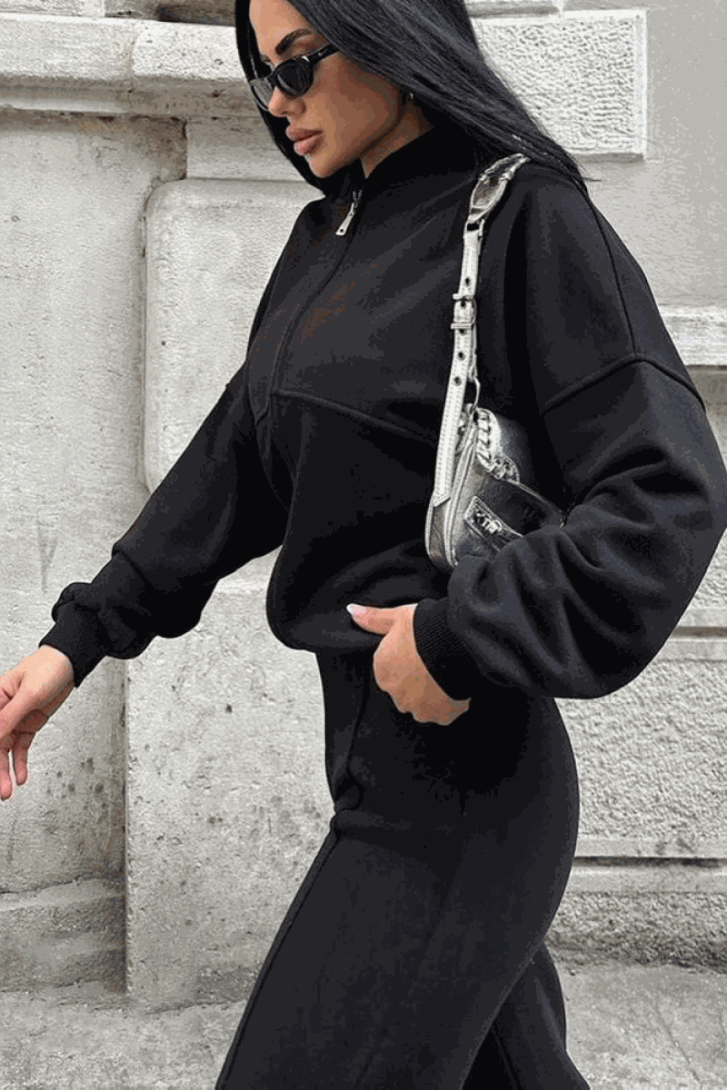 Woman wearing The Voyager Zip Set black zip-front sweatshirt and wide-leg joggers with pockets, styled for comfortable travel and casual wear