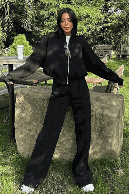 Woman wearing The Voyager Zip Set black zip-front sweatshirt and wide-leg joggers outdoors