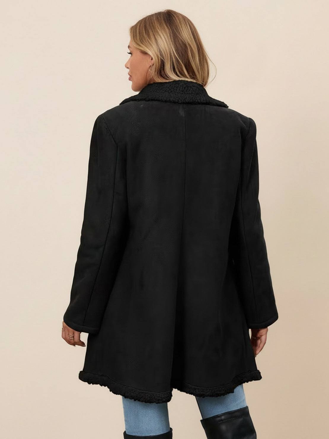 Woman wearing a mid-thigh faux suede sherpa coat with double-breasted front and contrast sherpa trim