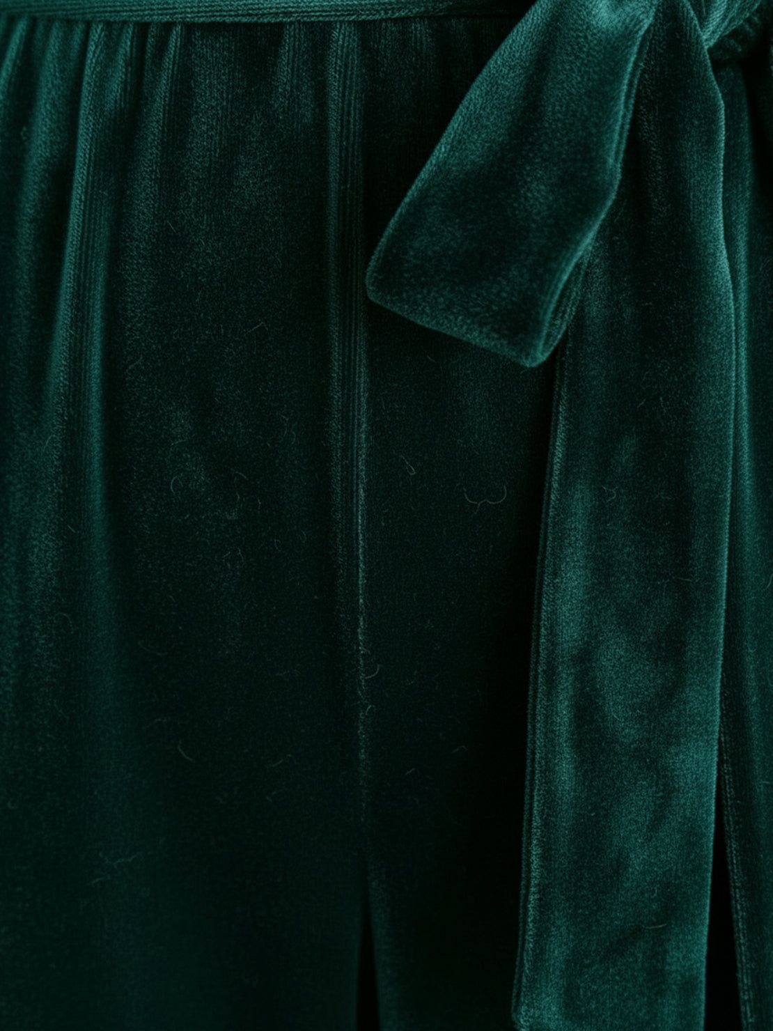 Woman wearing a deep V-neck velvet suit with long sleeves, removable waist tie, and wide-leg pants at an elegant event