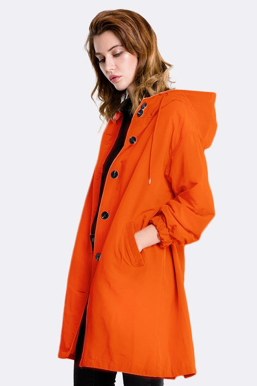 Orange oversized water-resistant windbreaker jacket with hood on woman model