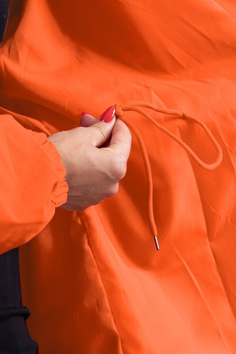 Close-up of orange water-resistant oversized windbreaker with adjustable drawstring on sleeve