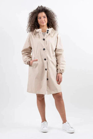 Beige oversized water-resistant windbreaker rain jacket with hood and button closure worn by woman