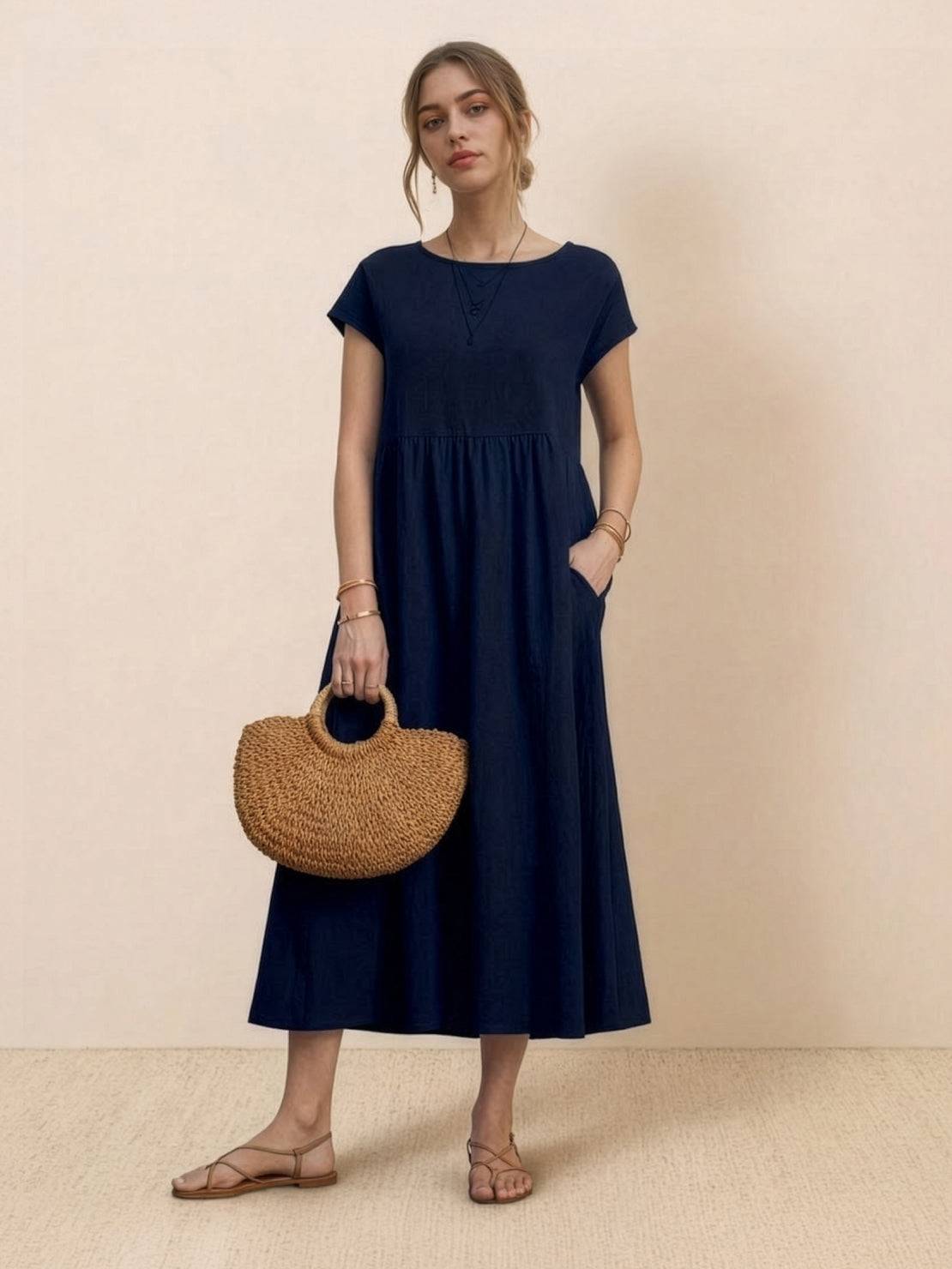 Woman wearing capped-sleeve voluminous pleated midi dress with flowing skirt and pockets