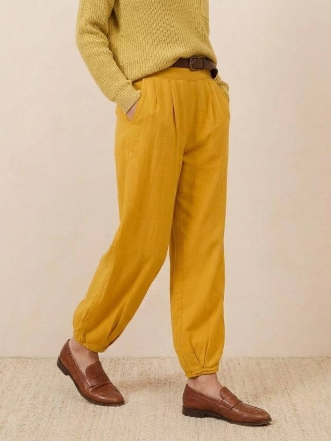 Woman wearing European minimalism casual relaxed sweater and mustard yellow trousers with brown loafers