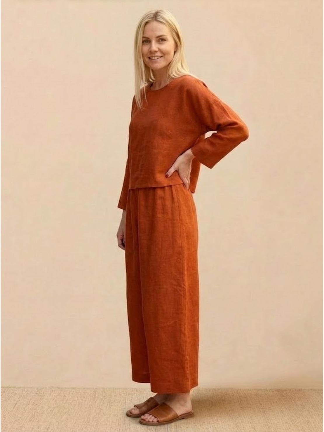Loose solid color two-piece set with loose fit, breathable fabric, and wide-leg pants in rust color worn by woman