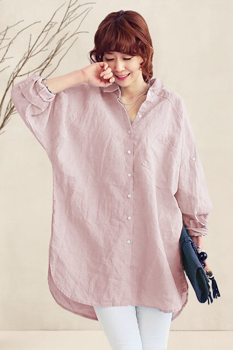 Woman wearing a pink oversized linen shirt with buttons and relaxed fit sleeves holding a clutch bag.