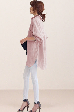 Woman wearing oversized linen shirt in sun-washed pink with rolled-up sleeves and white pants