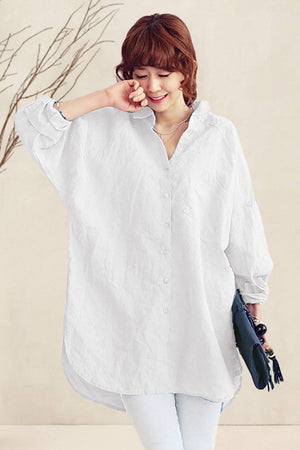 Woman wearing a relaxed fit oversized linen shirt in white with long sleeves and a flowing hemline