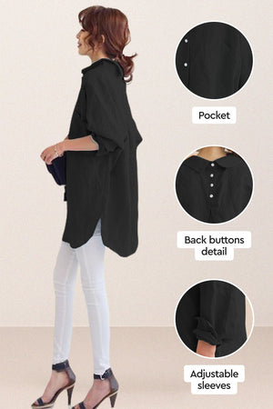 Black oversized linen shirt with back button detail, adjustable sleeves, and relaxed fit worn with white pants and heels.