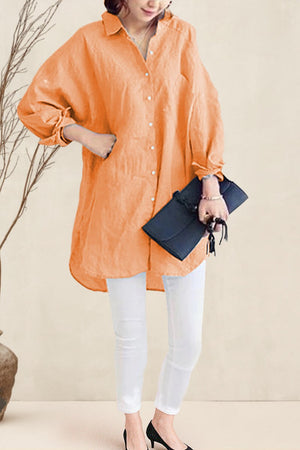 Women's oversized linen shirt in soft orange with relaxed fit and button-down front, styled with white pants and black heels.