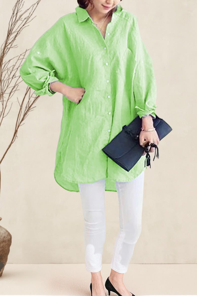 Woman wearing oversized linen shirt in light green with white pants and black heels, holding a black clutch bag.