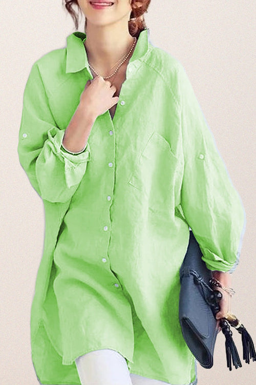 Light green oversized linen shirt with relaxed fit and button-down front worn by woman holding a black clutch
