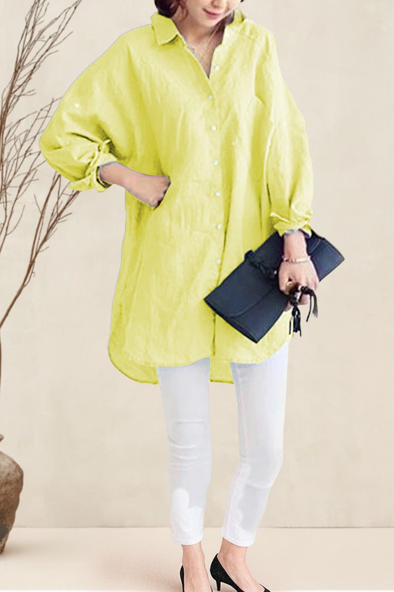 Oversized linen shirt in bright yellow with loose sleeves, worn with white pants and black clutch bag.