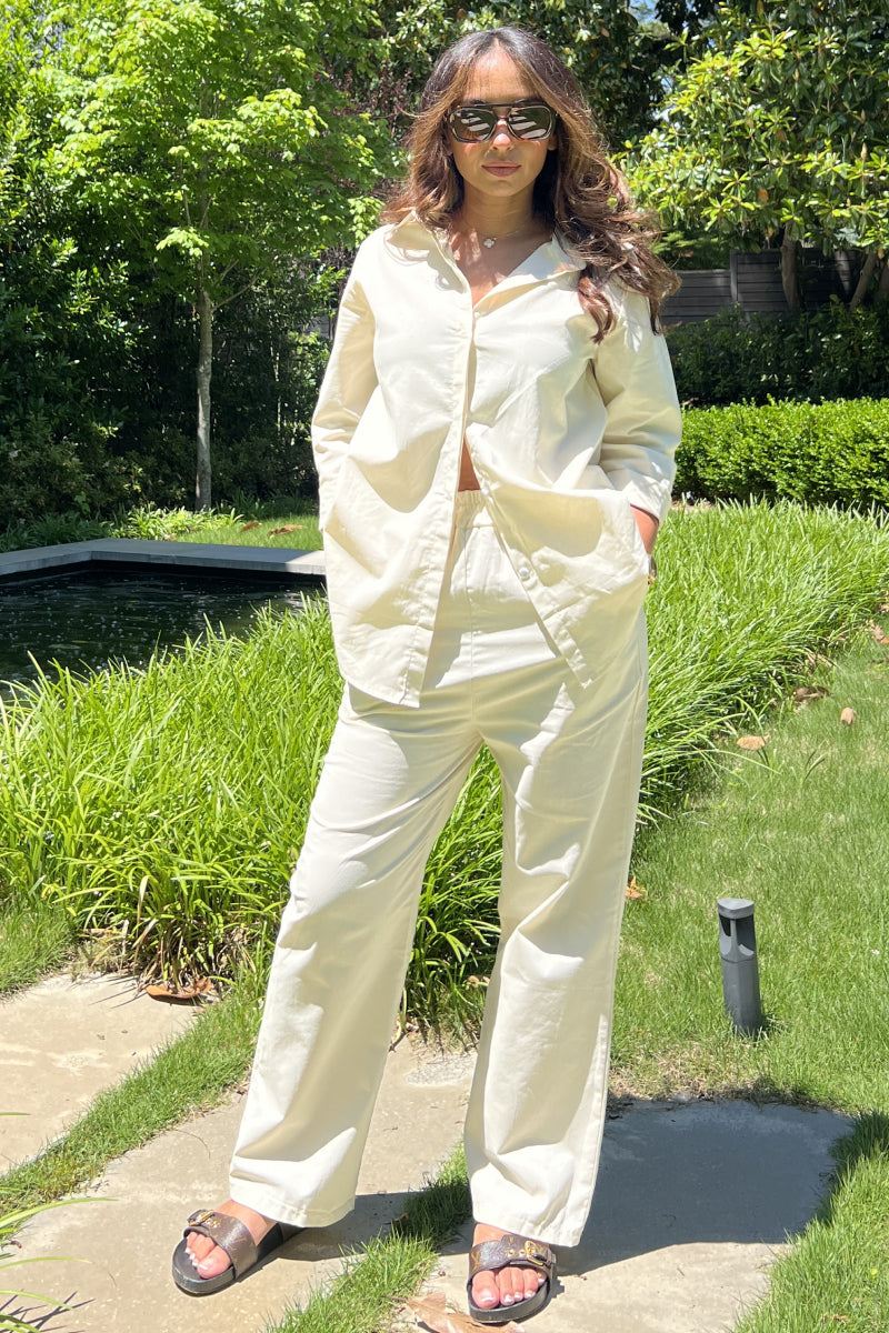 Woman wearing oversized 100% cotton shirt and wide-leg pants co-ord set in light cream outdoors