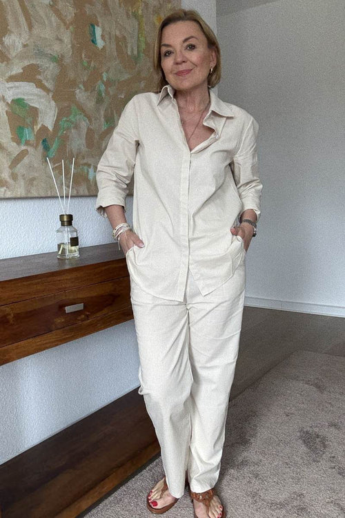 Woman wearing oversized 100% cotton shirt and wide-leg pants co-ord set in neutral tone indoors