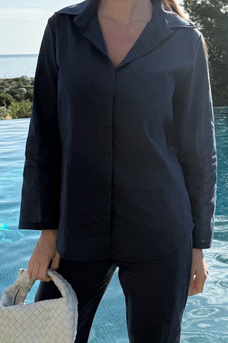 woman wearing oversized 100 cotton shirt and wide-leg pants co-ord set holding white woven handbag by poolside