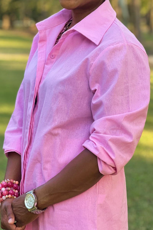 Close-up of a pink oversized 100% cotton shirt with rolled-up sleeves on a person outdoors