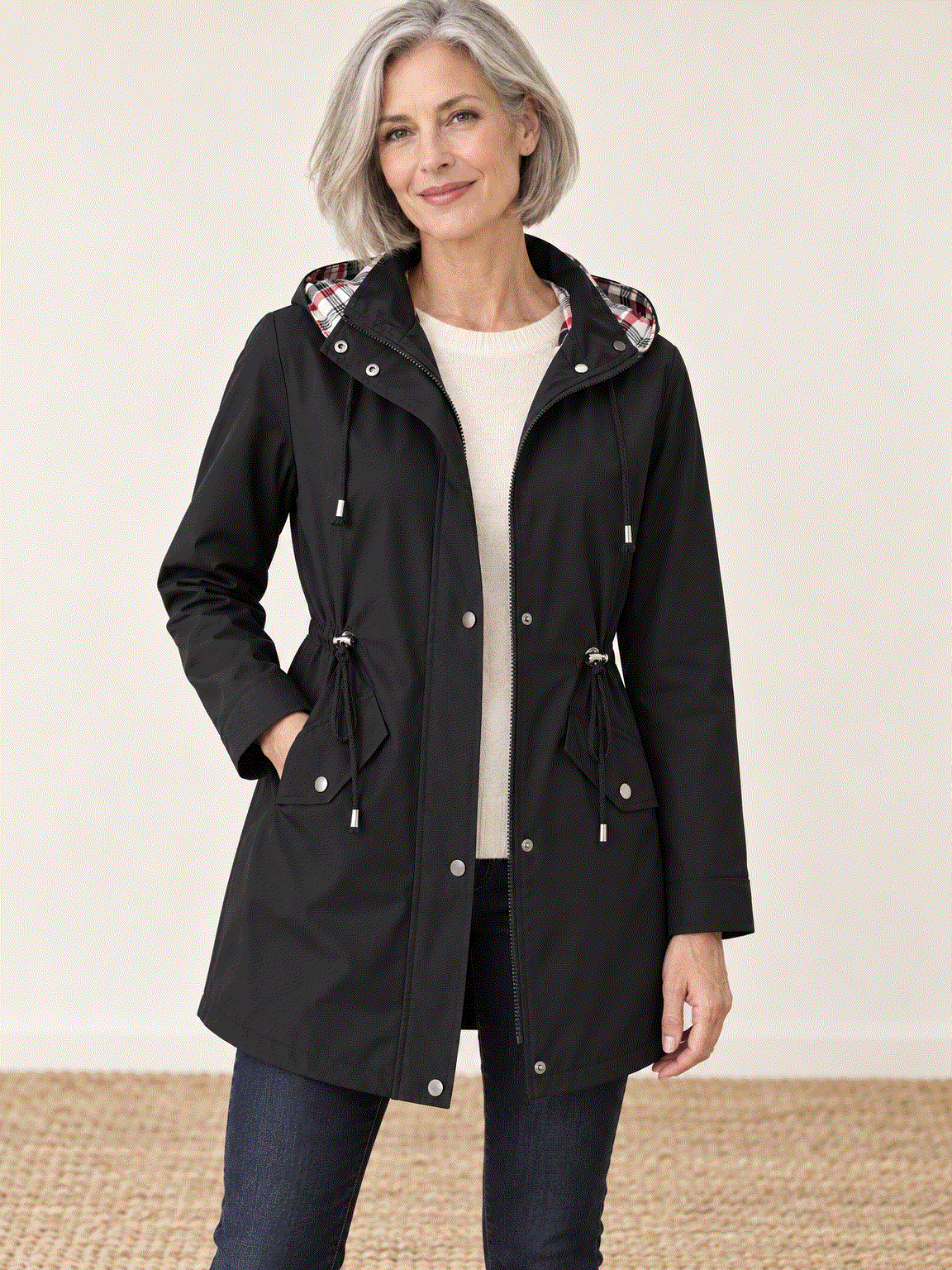 Women's plaid-lined hooded rain jacket with waterproof shell, adjustable drawstring waist, and snap flap pockets