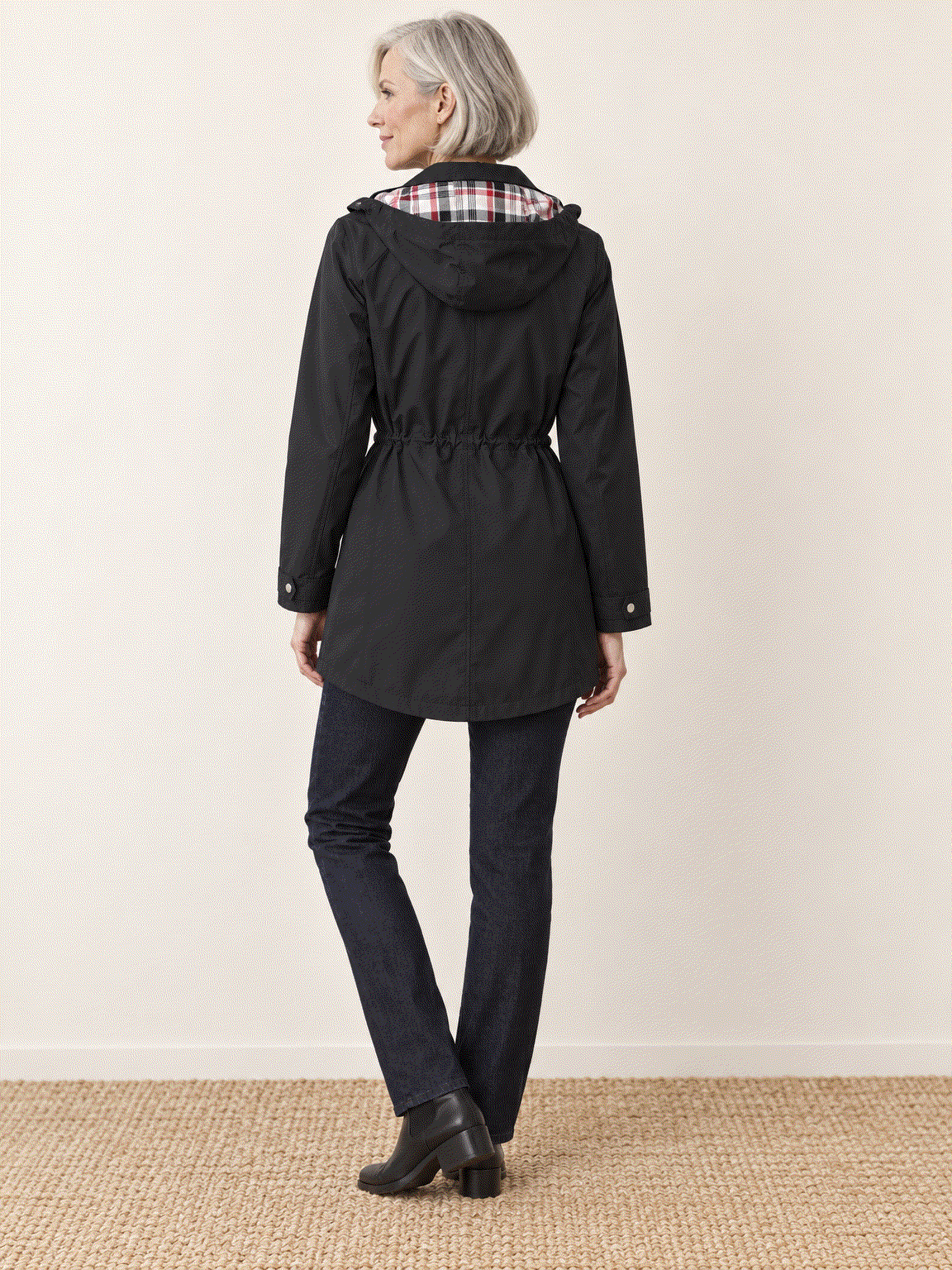 woman wearing plaid-lined hooded rain jacket with waterproof shell and tartan lining outdoors
