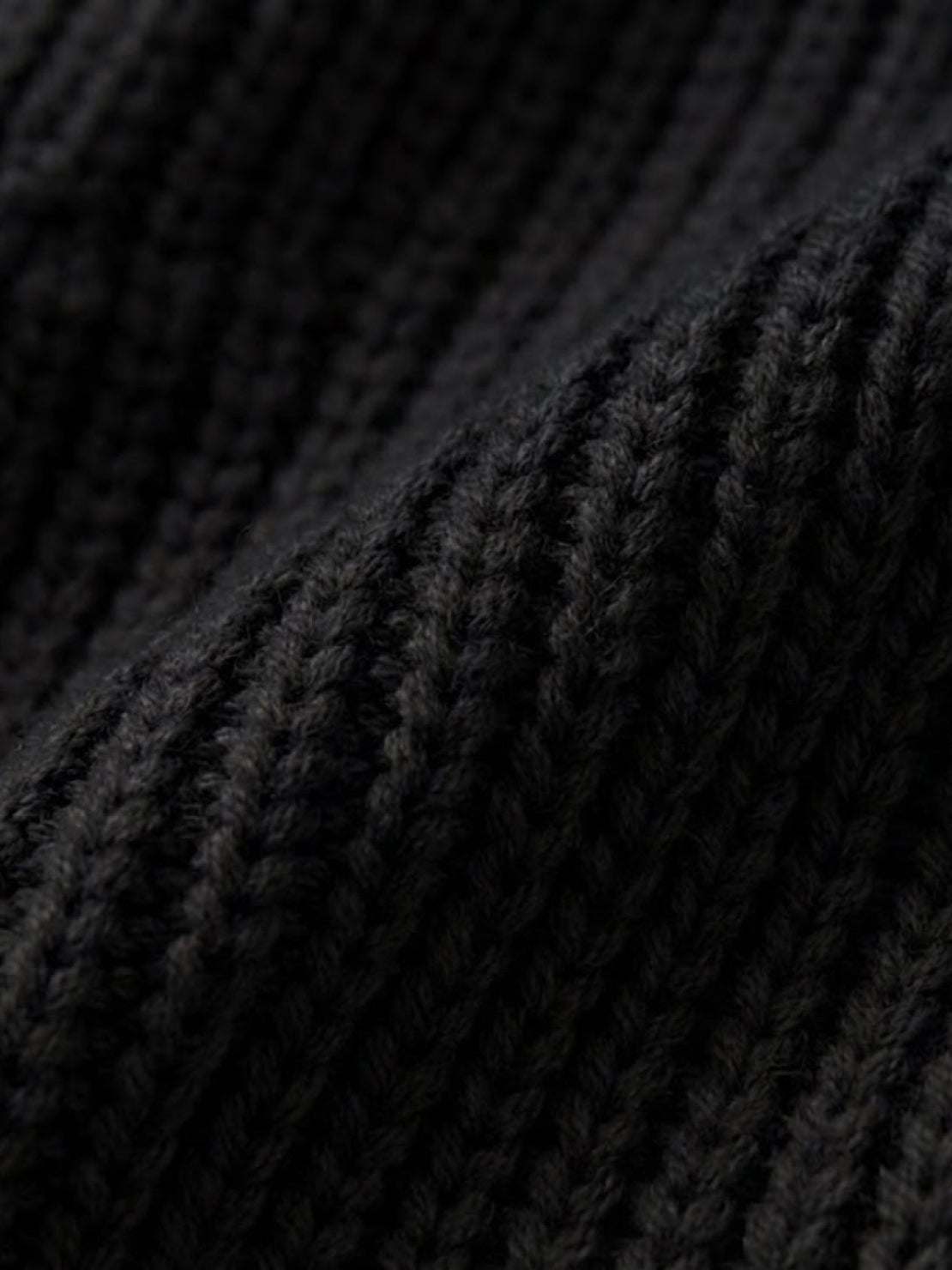 Close-up of black knit fabric texture for relaxed fit oversized cardigan