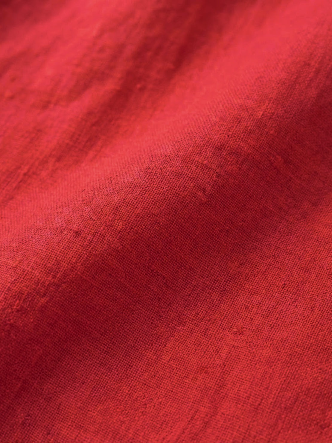 Close-up of vibrant red relaxed loose breathable linen fabric texture